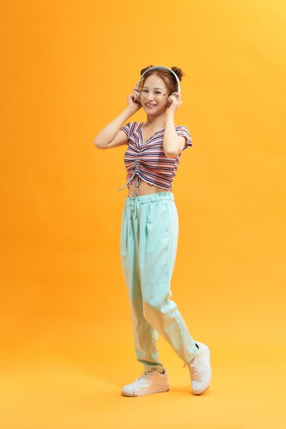 Image of happy young woman make winner gesture over yellow background. Look at camera.