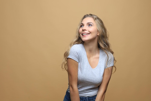 Image of happy young woman standing isolated over beige wall background.