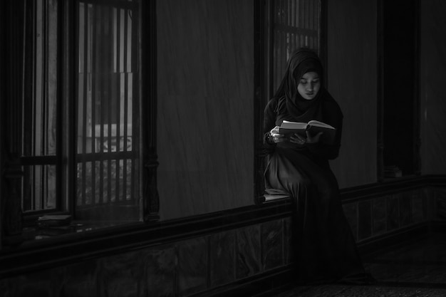 Image is Black and white. Muslim women wearing black shirts Doing prayer According to the principles of Islam.