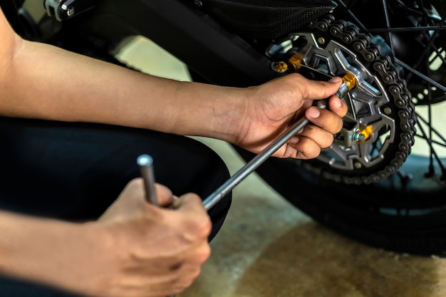 Image is Close up, Auto mechanic are repairing a motorcycle Use a wrench and a screwdriver to work.