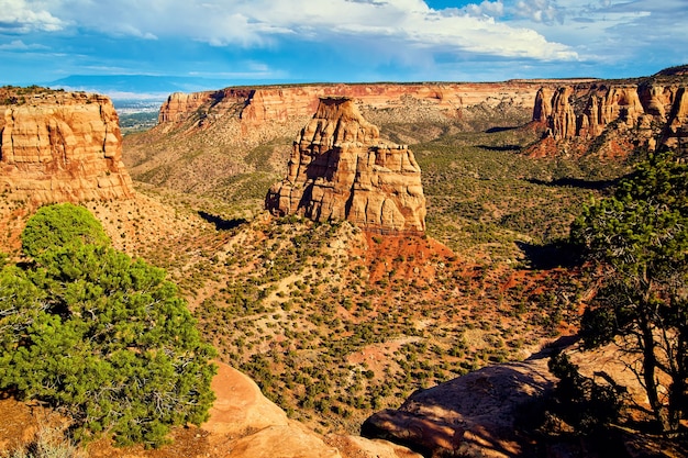 Image of Large red obelisk of rock in valley desert surrounded by mountains