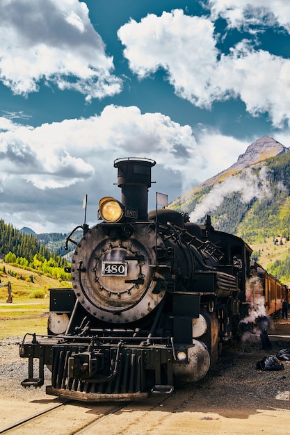 Image of Locomotive coal train in midwest mountains with large clouds