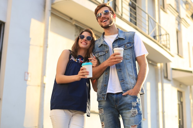 Image of lovely happy couple in summer clothes smiling and holding hands together while walking through city street.