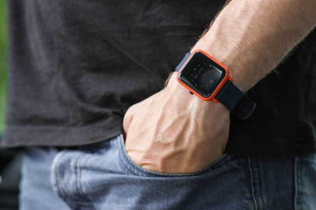 Image of man putting his hand in his jeans pants pocket wearing a smart watch Smart gadget concept