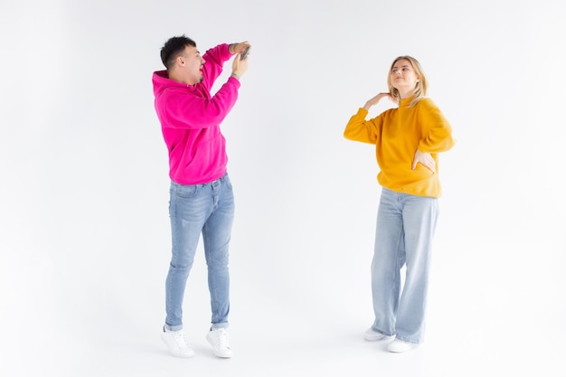 Image of a man take photo of his positive optimistic woman on white background by mobile phone