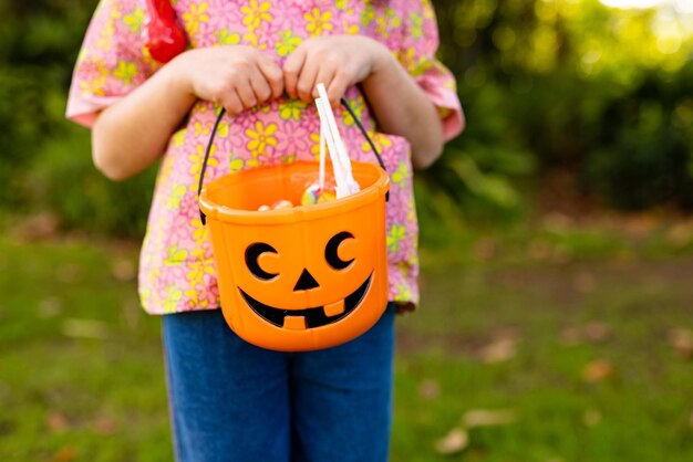 Photo image of midsection of caucasian girl in doctor costume in autumn garden. halloween, american culture and celebration concept.