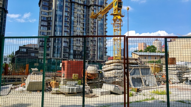 Image of modern building construction behind the wired fence at bright sunny day