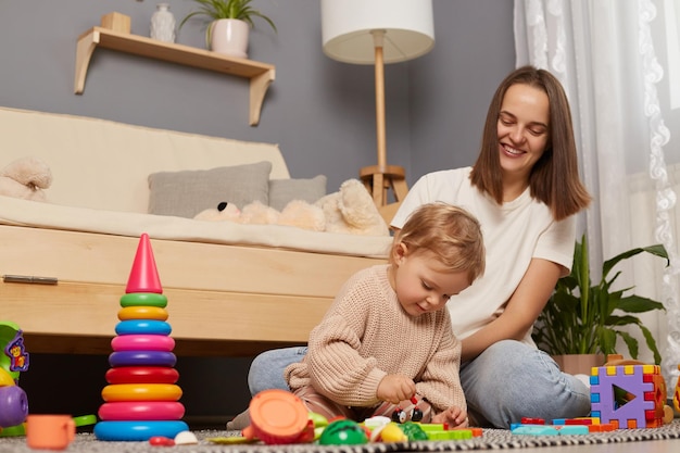 Image of mother playing with baby in the room spending time together early development caucasian family play educational games developing concentration