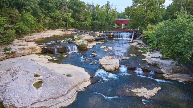 Image of Multiple waterfalls aerial shot at the Cataract Falls with a covered bridge in the background