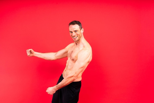 Image of muscle man posing in studio dark white red background