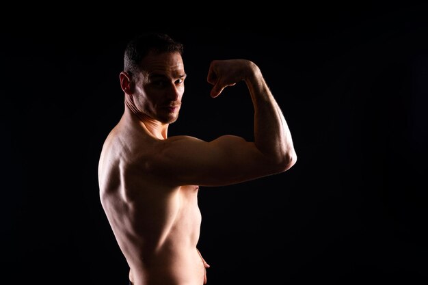 Immagine di un uomo muscolare che posa in studio sullo sfondo bianco-rosso scuro