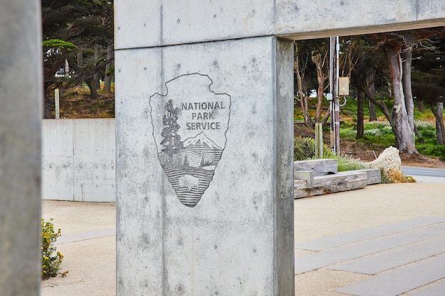 Image of National Park Service logo on concrete archway with Lands End Lookout park behind it