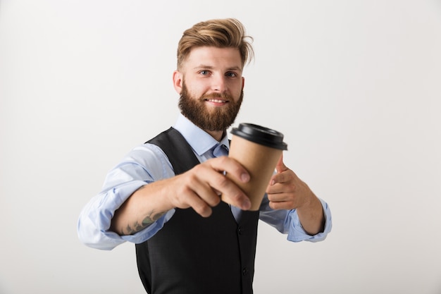 Фото Изображение красивого молодого бородатого человека, стоящего изолированно на фоне белой стены, пить кофе.