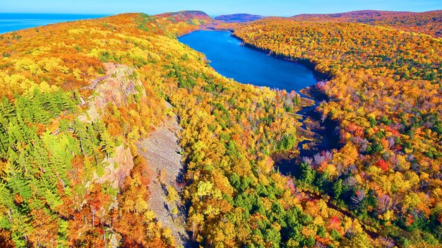 曲がりくねった川と金、緑、茶色、オレンジ、赤の秋の森と雲の中の空中湖の画像