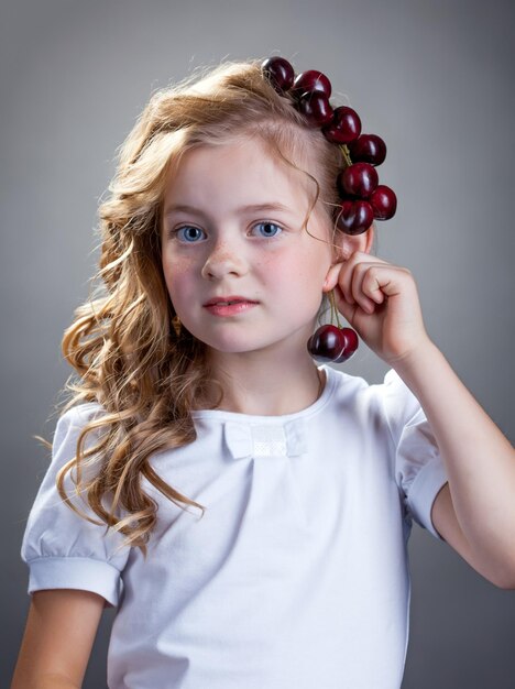 Фото Изображение милой девушки пробует вишни в качестве сережки