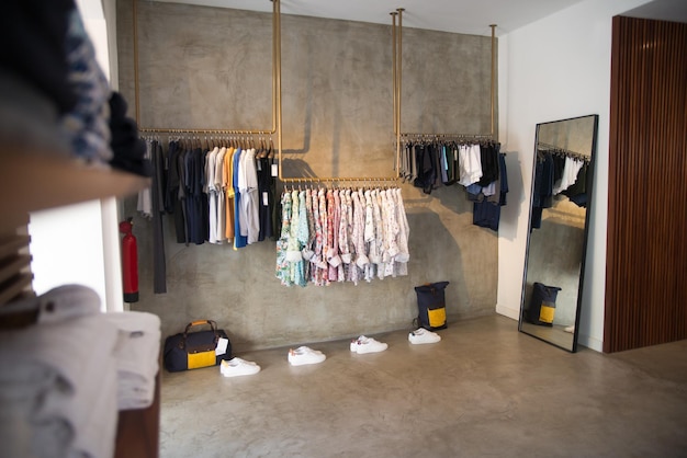 Фото Изображение магазина мужской одежды с мужской одеждой. комната с разной мужской одеждой, висящей на вешалках, и мужской обувью на полу. мужская мода, одежда и концепция покупок