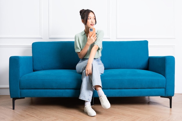 写真 自宅のソファに座っている若いアジアの女の子の画像