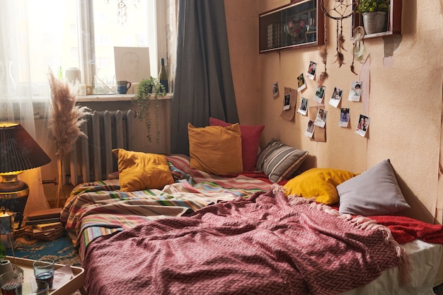 Image of old-fashioned room with bed with pillows and photos hanging on the wall in domestic room