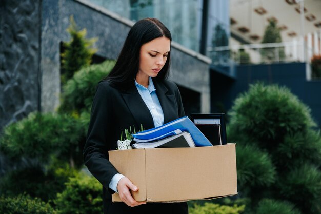 An image of a person holding a box with a look of sadness and joblessness on their face the aftermat