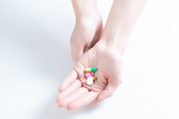 Image of pills on a female palm. The concept of medicine, health care, vitamins. Mixed media