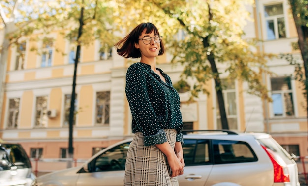 Image of positive beautiful young woman going to college Young female university student walking beside building campus in the city street