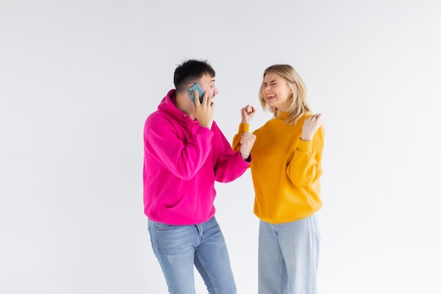 Image of positive optimistic loving couple isolated over white background talking by mobile phones