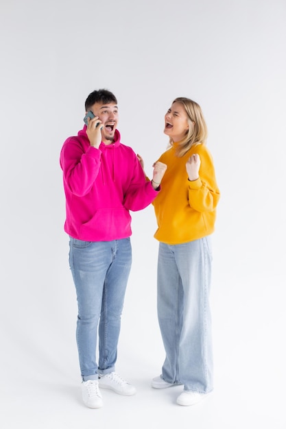 Image of positive optimistic loving couple isolated over white background talking by mobile phones