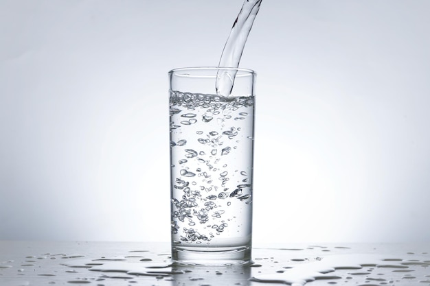 水のボトルからグラスに水を注ぐ画像