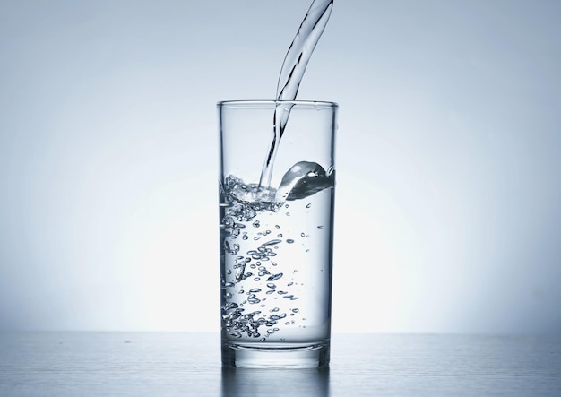 水のボトルからグラスに水を注ぐ画像