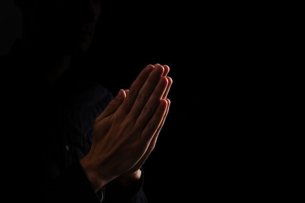 Image of praying hands on a black background