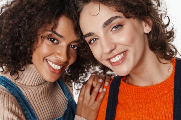 Image of a pretty happy smiling two multiracial girls friends in denim jumpsuits 