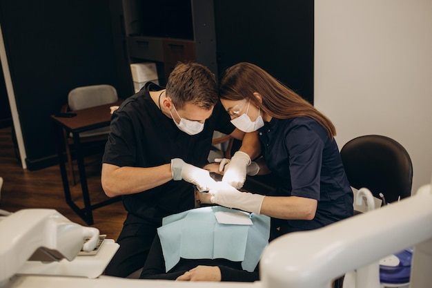 Image of pretty young woman sitting in dental chair at medical center while professional doctor fixing her teeth