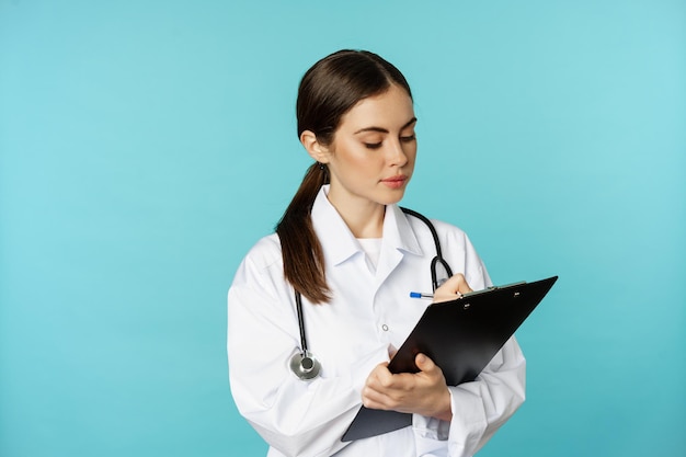 Image of professional woman doctor physician with clipboard writing listening patient at hospital cl...