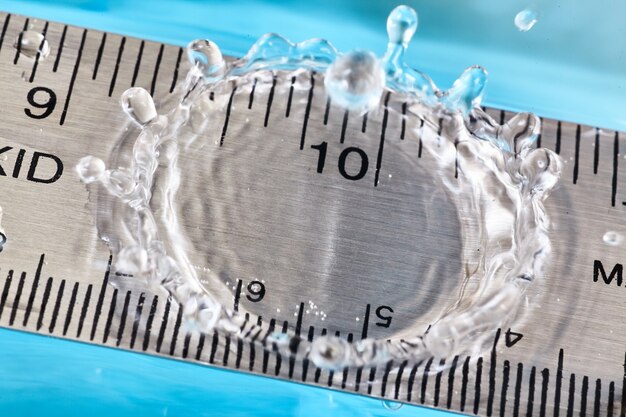 Image of Rebound water drop coming up off a ruler at the ten-inch mark