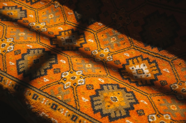 Image of a red ornamental carpet with lights nad shadows of a window on it.