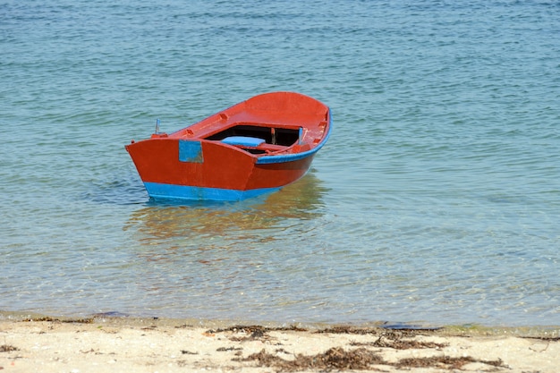 Image of red wooden fishing boat moored on the shore