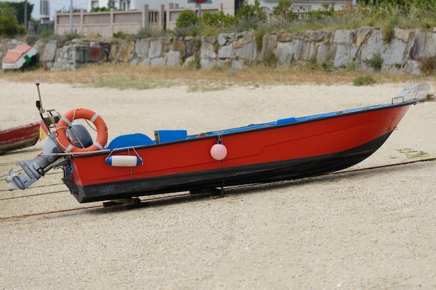 赤い木製の釣りモーターボートが岸に乾く画像