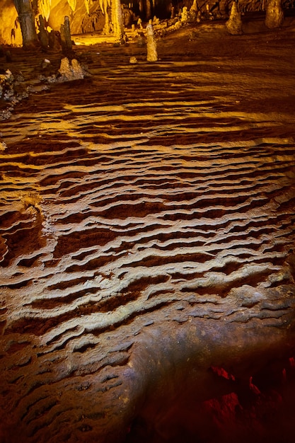 石筍と鍾乳石のある深い洞窟の岩の波紋の画像