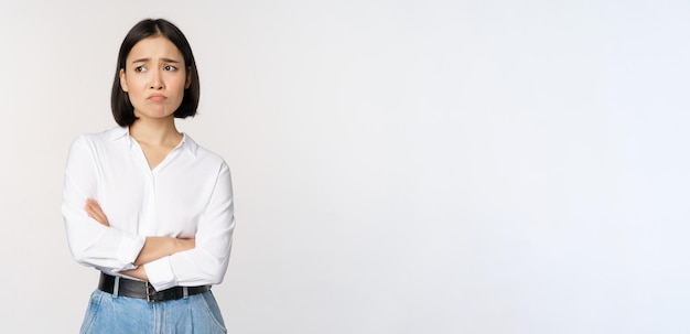 Image of sad office girl asian woman sulking and frowning disappointed standing upset and distressed against white background