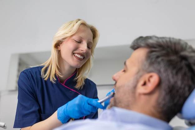 Image of satisfied man sitting in dental chair at medical center while professional doctor fixing his teeth