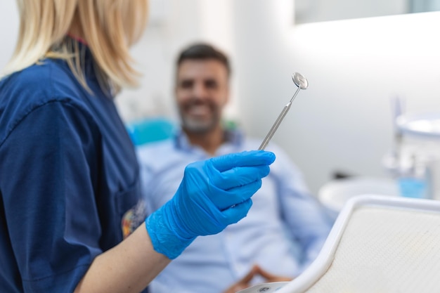 Foto immagine di un uomo soddisfatto seduto sulla poltrona del dentista al centro medico mentre un medico professionista si aggiusta i denti