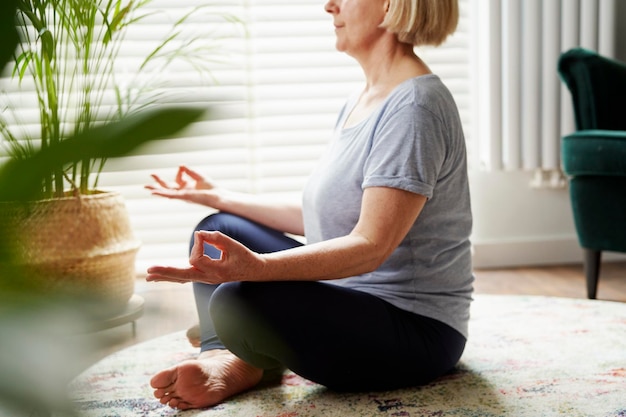 Image of senior woman meditating at home