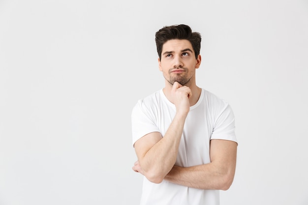 Photo image of a serious concentrated young man posing isolated over white wall .