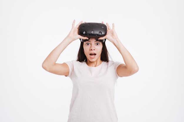 Image of shocked young woman wearing virtual reality device .