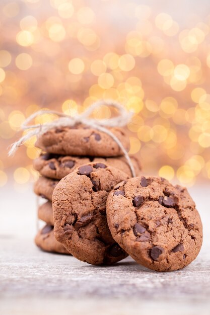 Image shows a stack of american chocolate chip cookies on rustic wooden plank.