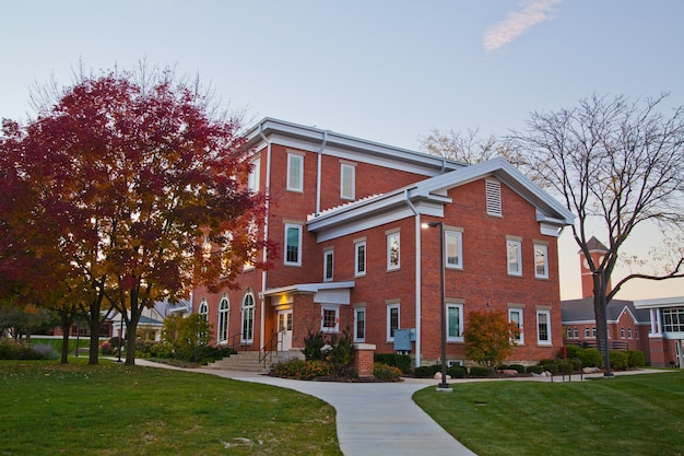 Image of Sidewalk leading through green lawns to a red brick Colonial style building