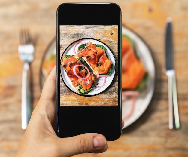 Изображение на экране смартфона вкусных тостов с копченым лососем