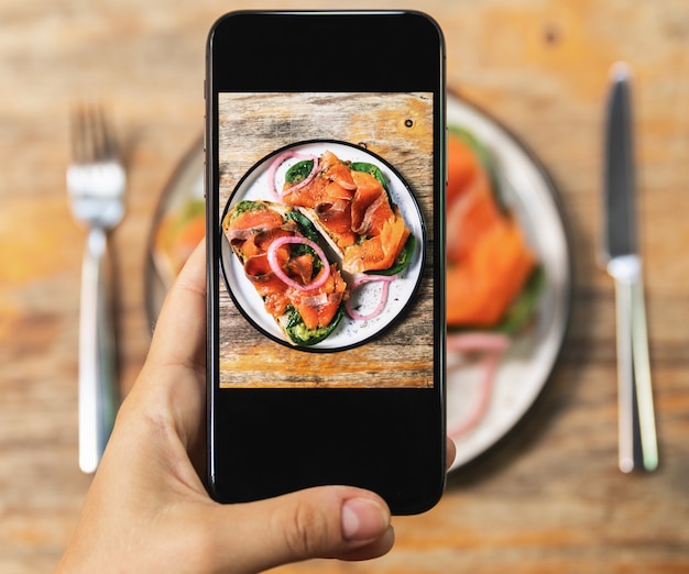 Photo image on smartphone screen of delicious toasts with a smoked salmon