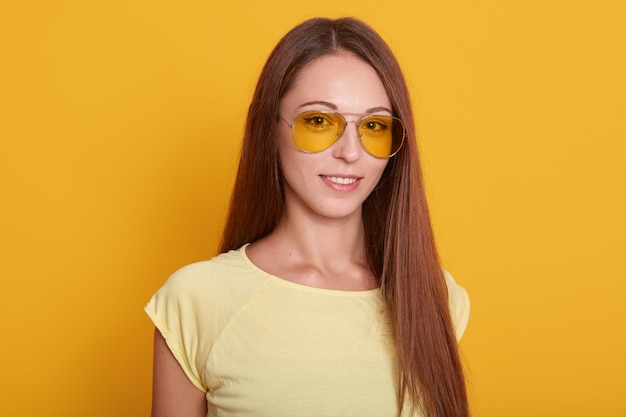 Image of smiling dark haired woman with perfect skin in eyeglasses posing and looking at camera