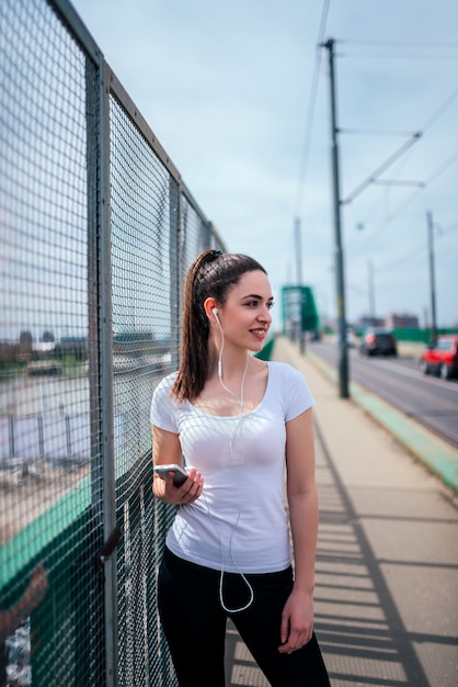 Image of sporty girl listening music outdoors, at the city.